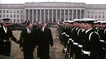 Movie still from “The Fog of War” (2003), directed by Errol Morris – A group of men standing next to each other in suits; Wide shot, Low angle