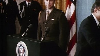 Movie still from “The Fog of War” (2003), directed by Errol Morris – A man in a military uniform standing at a podium; Medium shot, Low angle