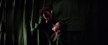 Movie still from “The Fortune” (1975), directed by Mike Nichols – Two men in a dark room with green drapes; Medium shot, Low angle