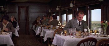 Movie still from “The Fortune” (1975), directed by Mike Nichols – A group of people sitting at a table in a restaurant; Wide shot, Over the shoulder angle