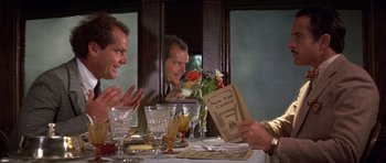 Movie still from “The Fortune” (1975), directed by Mike Nichols – Three men are sitting at a dinner table; Medium shot, Over the shoulder angle