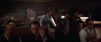 Movie still from “The Fortune” (1975), directed by Mike Nichols – A group of people sitting around a table; Medium shot, Over the shoulder angle
