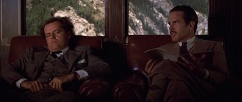 Movie still from “The Fortune” (1975), directed by Mike Nichols – Two men sitting on a train looking at each other; Medium shot, Over the shoulder angle