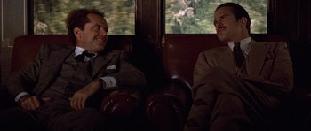 Movie still from “The Fortune” (1975), directed by Mike Nichols – Two men in suits sitting on a train car; Medium shot, Over the shoulder angle