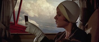 Movie still from “The Fortune” (1975), directed by Mike Nichols – A woman in a hat and gloves looking out a window; Close Up shot, Low angle