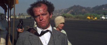 Movie still from “The Fortune” (1975), directed by Mike Nichols – A man in a suit and a woman in a white hat; Close Up shot, Over the shoulder angle