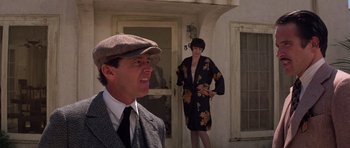 Movie still from “The Fortune” (1975), directed by Mike Nichols – A man and a woman standing in front of a building; Medium shot, Low angle