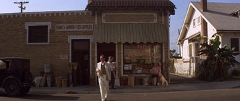 Movie still from “The Fortune” (1975), directed by Mike Nichols – A man walking down the street in front of a store; Wide shot, Low angle