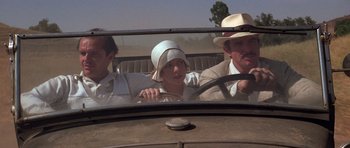 Movie still from “The Fortune” (1975), directed by Mike Nichols – A group of people riding in the back of an old car; Medium shot, Low angle