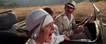 Movie still from “The Fortune” (1975), directed by Mike Nichols – A group of people sitting in a field eating food; Close Up shot, Low angle