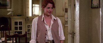 Movie still from “The Fortune” (1975), directed by Mike Nichols – A woman standing in front of a door wearing a vest; Medium shot, Over the shoulder angle