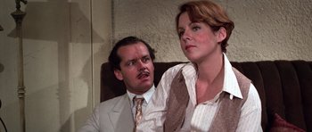 Movie still from “The Fortune” (1975), directed by Mike Nichols – A man and a woman sitting next to each other on a chair; Close Up shot, Over the shoulder angle