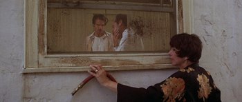 Movie still from “The Fortune” (1975), directed by Mike Nichols – A woman holding a whip in front of a mirror; Medium shot, Over the shoulder angle