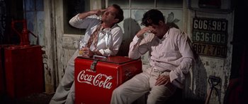 Movie still from “The Fortune” (1975), directed by Mike Nichols – A couple of men sitting next to each other on a bench; Medium shot, High angle