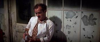 Movie still from “The Fortune” (1975), directed by Mike Nichols – A man wearing a tie in front of a wall; Medium shot, Low angle