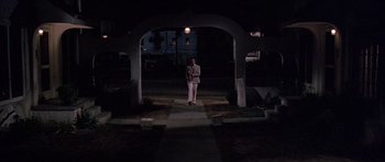 Movie still from “The Fortune” (1975), directed by Mike Nichols – A man standing in the middle of an archway at night; Wide shot, Low angle
