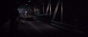 Movie still from “The Fortune” (1975), directed by Mike Nichols – A train on the tracks at night with lights on; Extreme Wide shot, Low angle