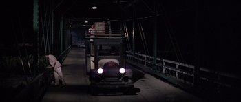 Movie still from “The Fortune” (1975), directed by Mike Nichols – An old truck is driving down a bridge; Wide shot, Low angle