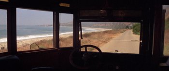 Movie still from “The Fortune” (1975), directed by Mike Nichols – A view of a beach from inside of a bus; Extreme Wide shot, High angle