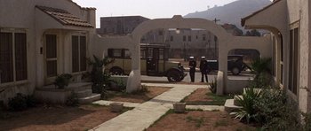 Movie still from “The Fortune” (1975), directed by Mike Nichols – A couple of men standing next to each other on top of a field; Extreme Wide shot, High angle