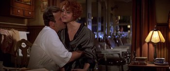 Movie still from “The Fortune” (1975), directed by Mike Nichols – A man and a woman are kissing in a restaurant; Medium shot, Over the shoulder angle