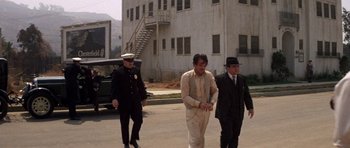 Movie still from “The Fortune” (1975), directed by Mike Nichols – A group of men walking down a street; Wide shot, High angle