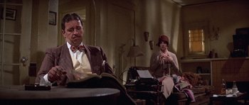 Movie still from “The Fortune” (1975), directed by Mike Nichols – A man and a woman sitting at a table; Medium shot, Low angle