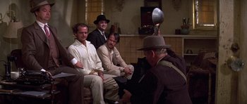 Movie still from “The Fortune” (1975), directed by Mike Nichols – A group of men sitting on top of a couch; Wide shot, Low angle
