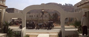 Movie still from “The Fortune” (1975), directed by Mike Nichols – A group of men standing next to an antique car; Extreme Wide shot, High angle