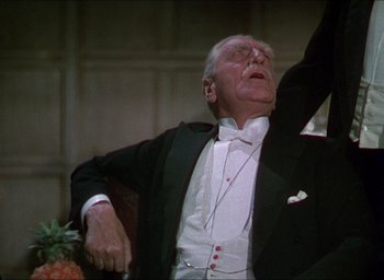 Movie still from “The Four Feathers” (1939), directed by Zoltan Korda – An older man in a tuxedo sitting in a chair; Medium shot, Low angle