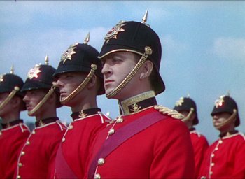 Movie still from “The Four Feathers” (1939), directed by Zoltan Korda – A group of men in red and black uniforms and hats; Medium shot, Low angle