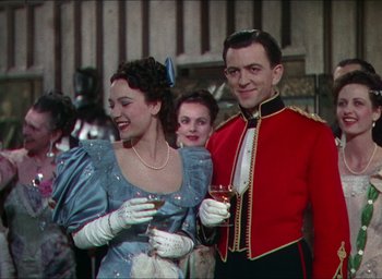 Movie still from “The Four Feathers” (1939), directed by Zoltan Korda – A man and a woman are standing next to each other holding wine glasses; Medium shot, Over the shoulder angle