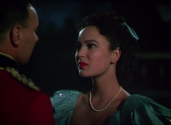 Movie still from “The Four Feathers” (1939), directed by Zoltan Korda – A woman with red lipstick and a pearl necklace looks at a man; Close Up shot, Over the shoulder angle