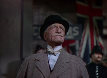 Movie still from “The Four Feathers” (1939), directed by Zoltan Korda – An old man wearing a hat and a bow tie; Medium shot, Low angle