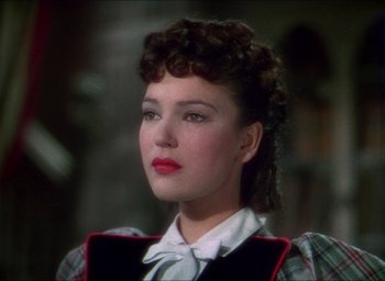 Movie still from “The Four Feathers” (1939), directed by Zoltan Korda – A young woman with curly brown hair wearing a red and black plaid shirt; Close Up shot, High angle