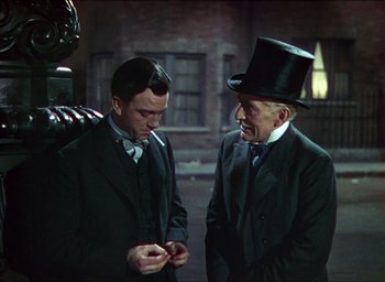Movie still from “The Four Feathers” (1939), directed by Zoltan Korda – Two men in suits and top hats are talking to each other; Medium shot, Over the shoulder angle