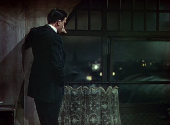 Movie still from “The Four Feathers” (1939), directed by Zoltan Korda – A man standing in front of a window at night; Medium shot, Over the shoulder angle