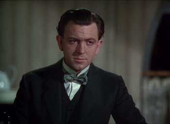 Movie still from “The Four Feathers” (1939), directed by Zoltan Korda – A person wearing a suit and a bow tie; Close Up shot, Over the shoulder angle