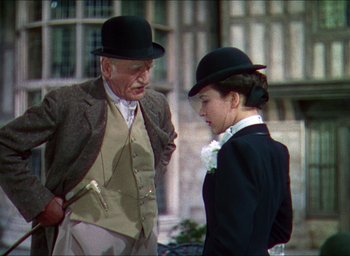 Movie still from “The Four Feathers” (1939), directed by Zoltan Korda – An older man and a young woman wearing hats; Medium shot, Over the shoulder angle
