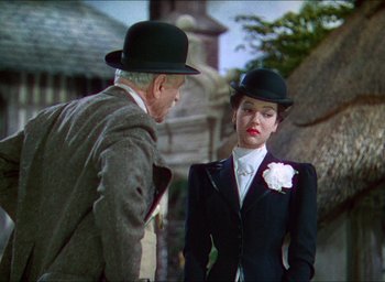Movie still from “The Four Feathers” (1939), directed by Zoltan Korda – An older man and a young woman wearing hats; Medium shot, Over the shoulder angle