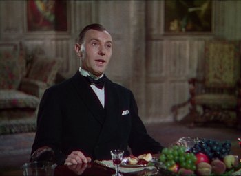 Movie still from “The Four Feathers” (1939), directed by Zoltan Korda – A man sitting at a table with a plate of food; Medium shot, Over the shoulder angle