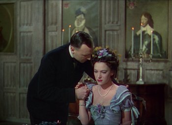 Movie still from “The Four Feathers” (1939), directed by Zoltan Korda – A man and a woman in formal dress in front of a painting; Medium shot, Over the shoulder angle