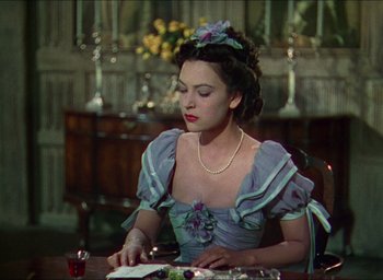 Movie still from “The Four Feathers” (1939), directed by Zoltan Korda – A woman sitting at a table writing on a piece of paper; Medium shot, Over the shoulder angle