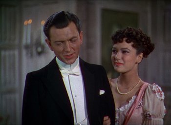 Movie still from “The Four Feathers” (1939), directed by Zoltan Korda – A man and a woman standing next to each other in formal wear; Medium shot, High angle