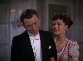 Movie still from “The Four Feathers” (1939), directed by Zoltan Korda – A man and a woman standing next to each other in formal wear; Close Up shot, Low angle