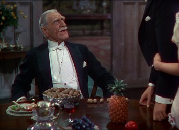Movie still from “The Four Feathers” (1939), directed by Zoltan Korda – An old man sitting at a table with a bowl of pineapples; Medium shot, Over the shoulder angle
