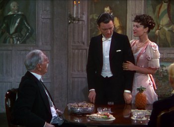 Movie still from “The Four Feathers” (1939), directed by Zoltan Korda – A group of people standing around a table with a cake; Medium shot, High angle