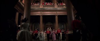 Movie still from “The Four Feathers” (2002), directed by Shekhar Kapur – A group of people dressed in formal attire in front of an audience; Extreme Wide shot, Low angle
