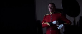 Movie still from “The Four Feathers” (2002), directed by Shekhar Kapur – A man in a red and gold uniform standing with his arms crossed; Medium shot, Low angle