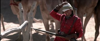 Movie still from “The Four Feathers” (2002), directed by Shekhar Kapur – A man in a red coat and a white hat holding a rifle; Medium shot, Low angle